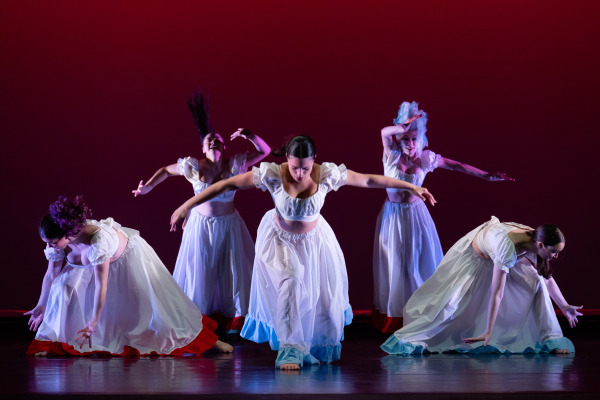 A group of women in white dresses dancing onstage