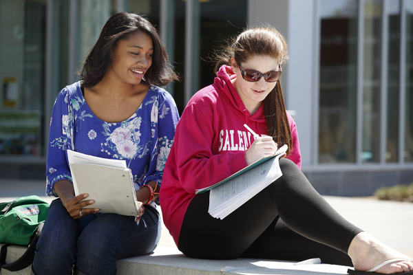 Two young girls sit side by side studying. 