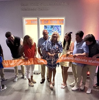 Sally Cioffi, mother of Sam Cioffi, cuts the ceremonial ribbon surrounded by members of the Cioffi family and Salem State University officials.