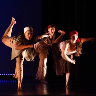 Trio of dancers with legs raised behind them