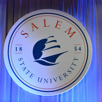 University seal hung in fron of a blue curtain