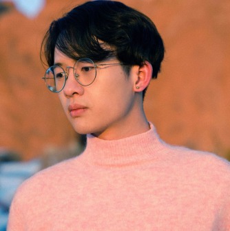 Shangyang Fang in a pink turtleneck in front of a tree