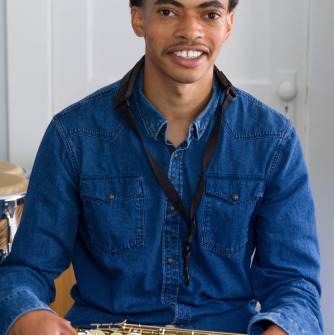 Man in blue shirt holding a saxophone