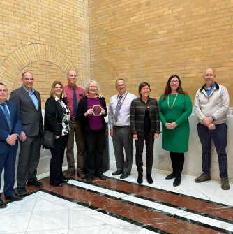 Tara Gallagher, at center holding the Leading By Example award, with DOER Commissioner Elizabeth Mahoney, other state officials and colleagues in Salem State's Sustainability and Environmental Health and Safety division.