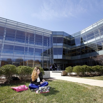 Student in front of the Berry library sitting in the grass reading