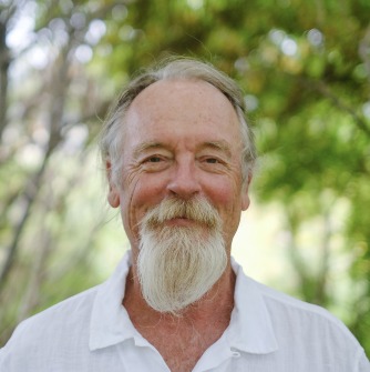 Man with with white beard in front of trees