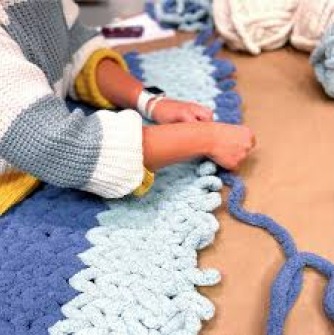 Participant weaving two blue colors to create a blanket