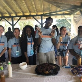 Image of students at a Day of Service event under a tent with food on a table