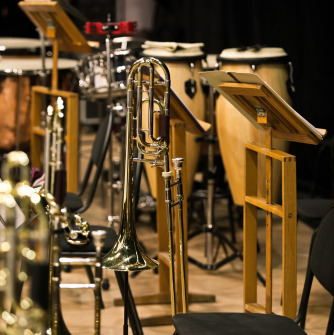 Trombones on trombone stands on a stage