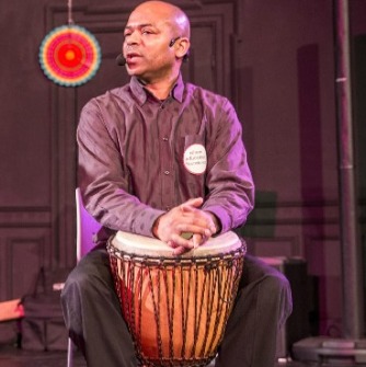 Man sitting behind a tall drum