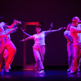 Six dancers in pink light on the stage