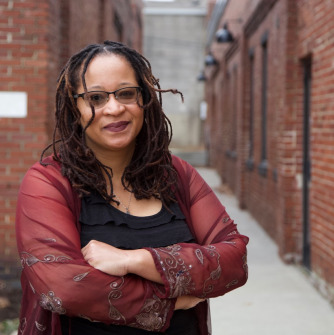 Woman in red and black standing in front of brick wall