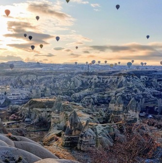 Hundreds of hot air balloons ascend at dawn over Cappadocia, Turkey. The balloons give passengers a great view of the unique rock formations and beautiful walking trails below.