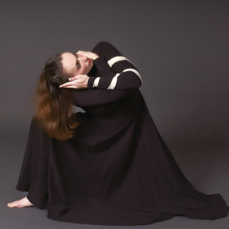 Women blessed in a black dress kneeling on the floor.