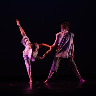 Once dancer with leg extended in the air and holding the hand of another dancer