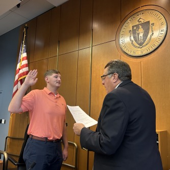 Student Trustee Matthew Beckett raising his hand as he is sworn in for his position.