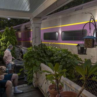 Two men sitting on a porch as a train passes by