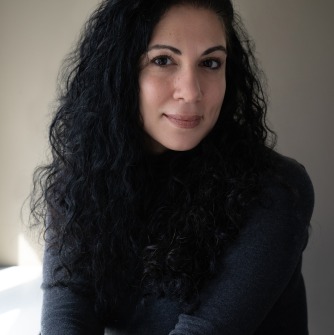 Susan Muaddi Darraj headshot smiling and wearing a dark sweater
