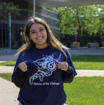 A student volunteer smiling in front of Marsh Hall