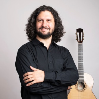 Man wearing black shirt and holding a guitar