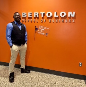 Emmanuel Ayodele stands next to the Bertolon School of Business sign