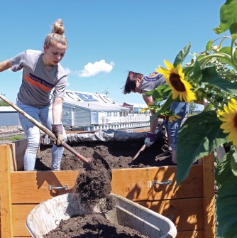 A Salem State University student and volunteer helps work on a community garden at Palmer Cove, an affordable housing community outside of The Point in Salem.