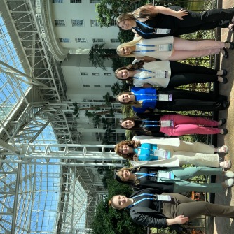 A group of eight conference attendees are pictured standing together in front of a building.