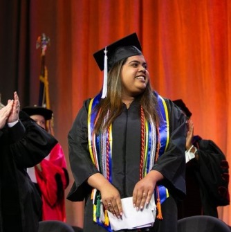 Anngerline Burgos standing on the stage at commencement