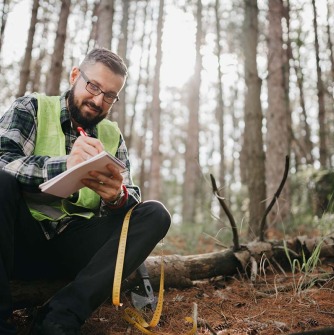 A man in the woods recording data