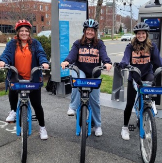 Three students ride Bluebikes on the rail trail