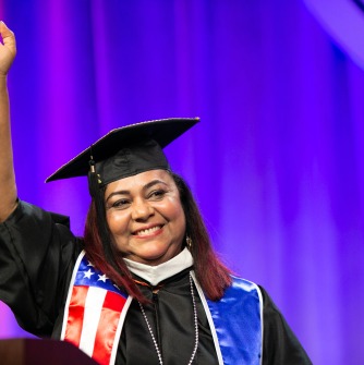 Martha Cecilia Valentin waves to the audience from the podium at commencement.