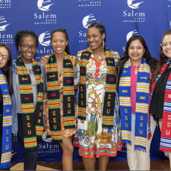 Salem State students smile for the camera in ALANA graduation cords.