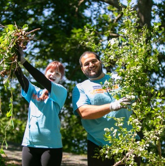Two students holding up bittersweet plants that they removed off Winter Island