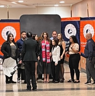 Student posing for a photo with family and friends in front of university flags