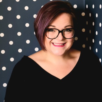Justine Bodek headshot. Justine smiles in front of a polka dot background.