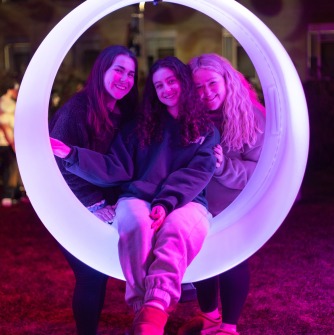 Three students in the round outdoor swing at fall fest