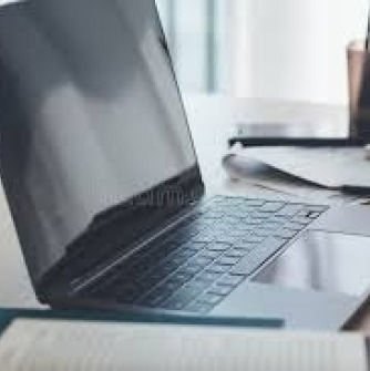 Laptop, notebook, and container of pens on desk