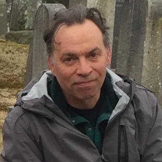 J.D. Scrimgeour seated outside wearing a gray jacket