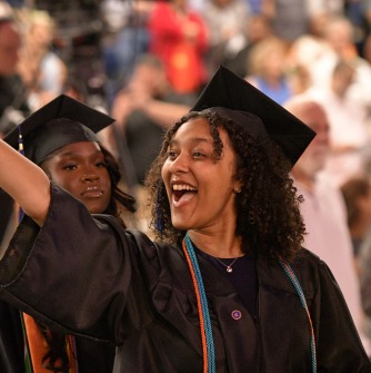 Graduate in the procession waving excitedly