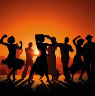 Silhouettes of dancers against an orange sky