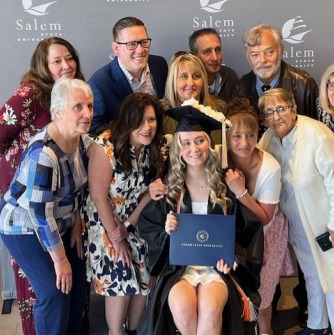 Family members pose with a graduate in front of Salem State photo backdrop