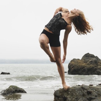 Woman dancing on a beach near rocks