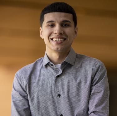 Anthony Flores pictured in the library in a light-colored dress shirt