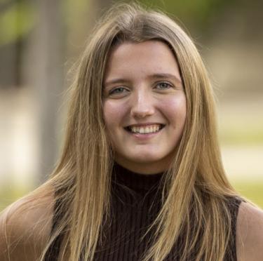 Sierra Dearns wearing a brown turtleneck and smiling at the camera