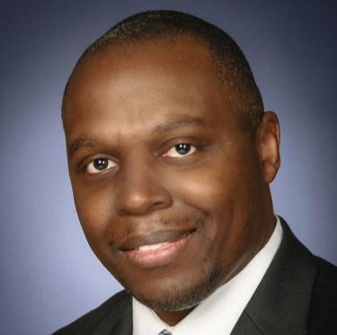 Lamont Simmons wearing a dark-colored suit with white dress shirt