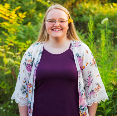 Paige Bowen pictured in a field with a floral caftan and purple dress