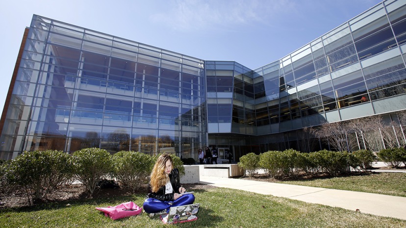 Student in front of the Berry library sitting in the grass reading