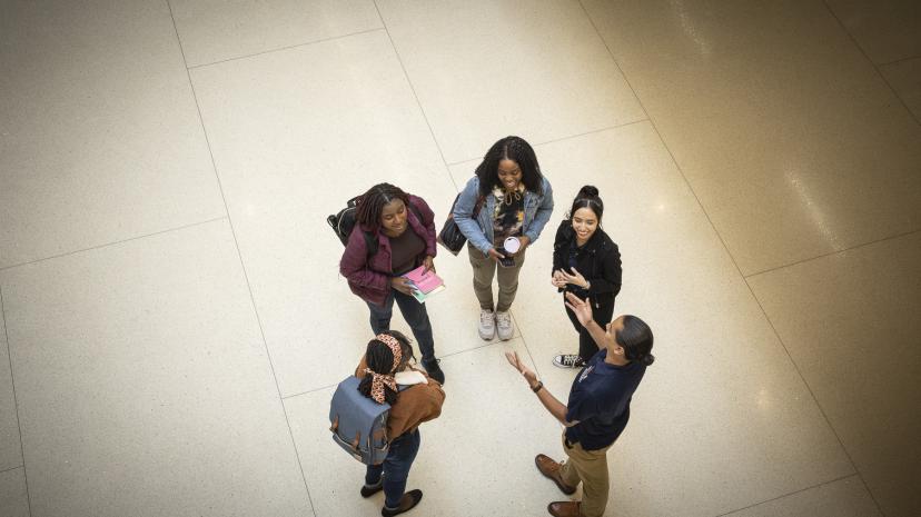 Group of five students standing in a circle in the entrance of the library
