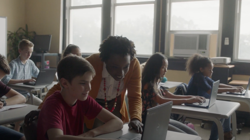 Teacher in an elementary classroom working with a young student