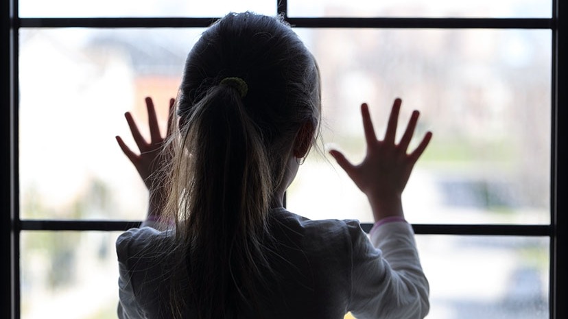 Image of a young female child pressing her hands against a window